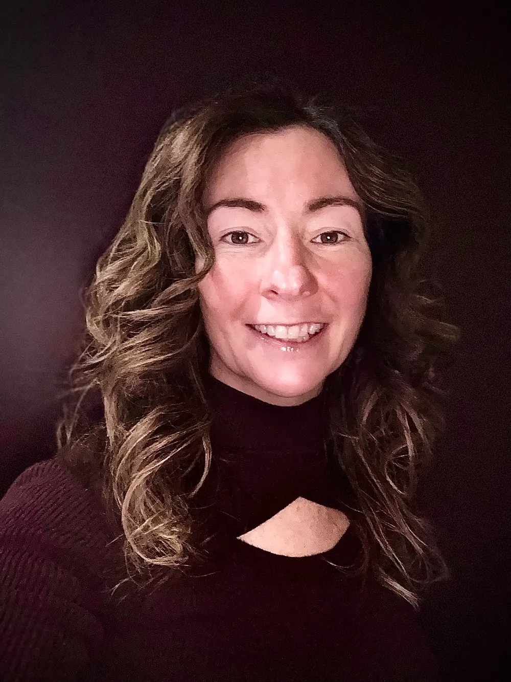 Lynette Tidy, smiling, in a dark roll-neck top