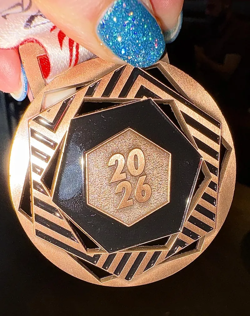 A bronze-coloured 2026 medal held up to the camera